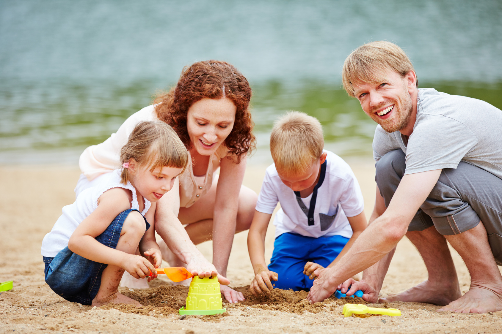 Familie mit Kindern spielt im Sand am Strand